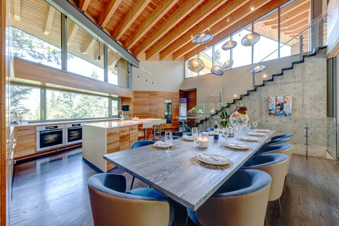 Comedor con una mesa larga puesta junto a una cocina y una escalera.