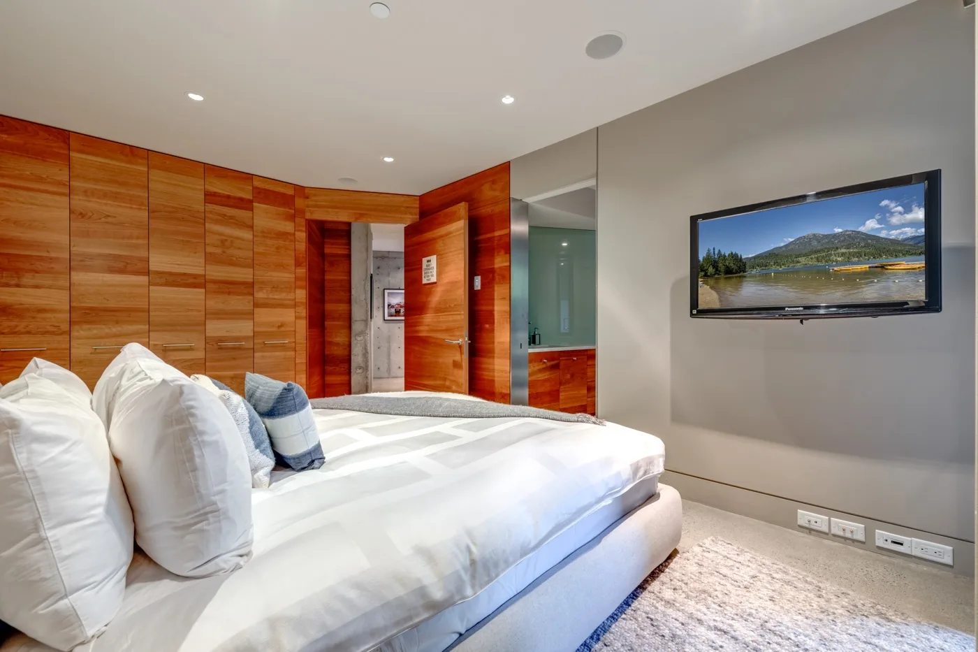 Un dormitorio con una cama grande, paneles de madera y un televisor.