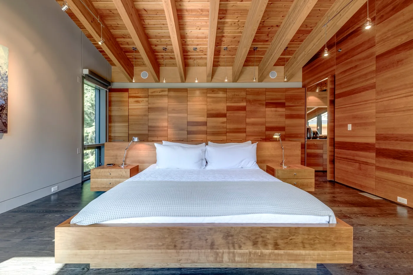 Un dormitorio con una cama baja de madera y un techo de vigas expuestas.
