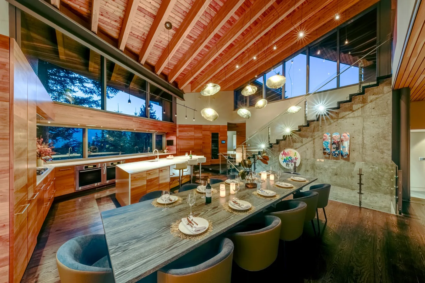 Un comedor con una mesa larga está junto a una cocina abierta bajo un techo de madera.