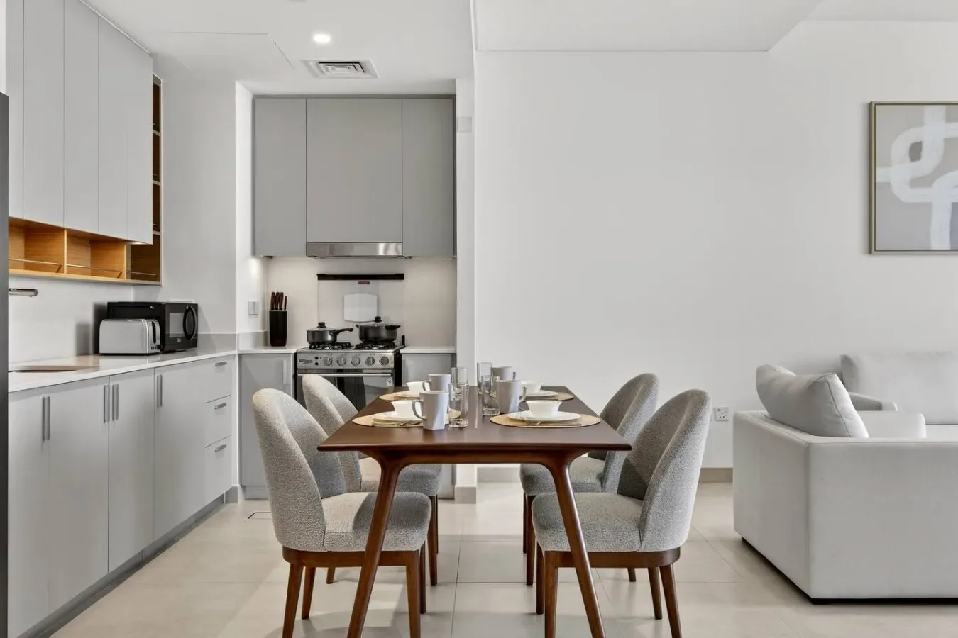 Un comedor con la mesa puesta está junto a una cocina.