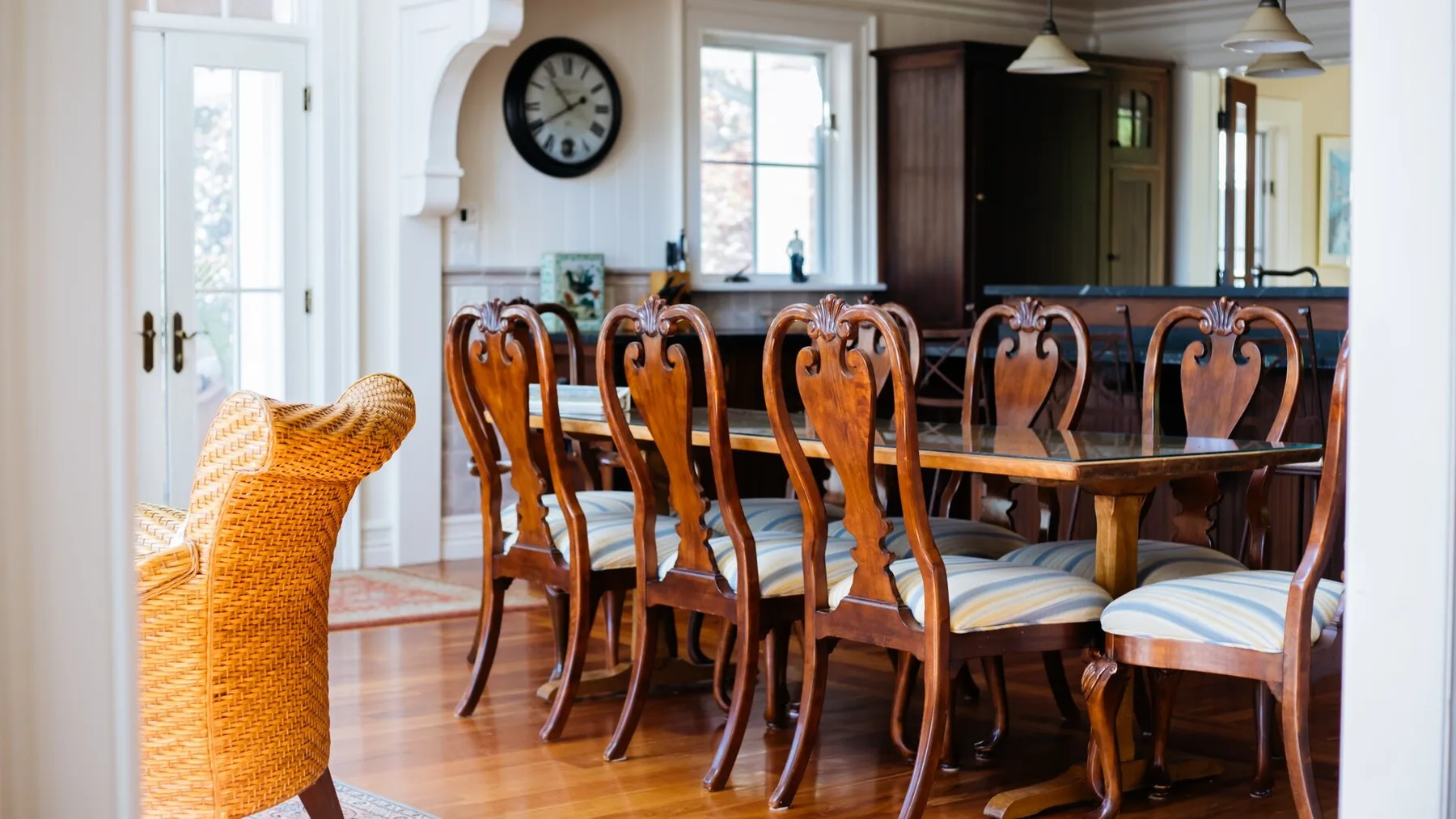 A dining room with a long wooden table and upholstered chairs.
