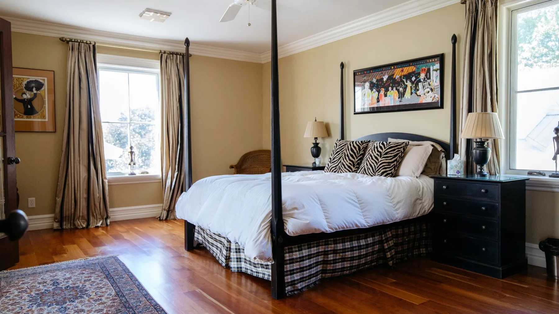 A bedroom with a bed, framed artwork, and windows overlooking trees.