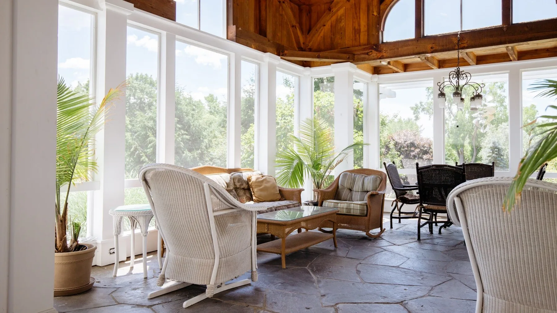A bright sunroom with seating, a dining table, and large windows.