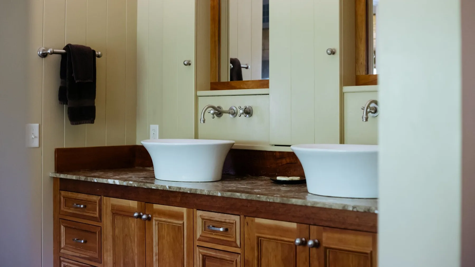 A bathroom vanity with two sinks, mirrors, and wooden cabinets.