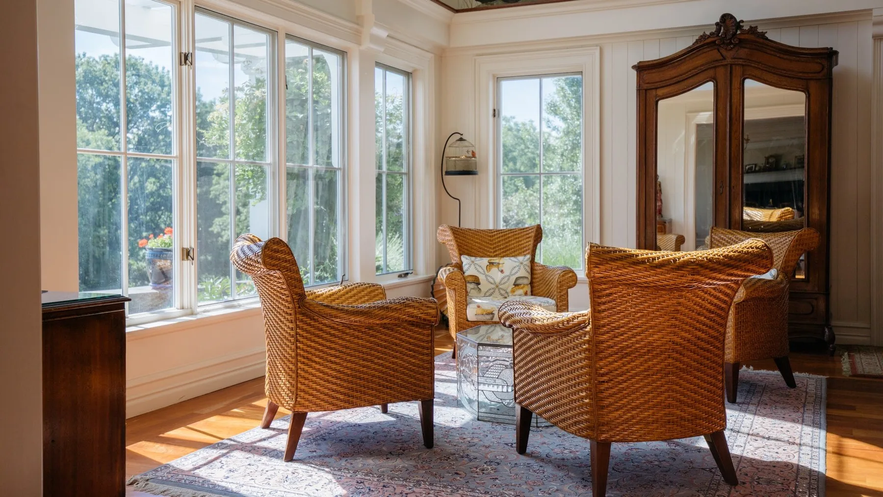 A bright sitting room with wicker seating beside tall windows.
