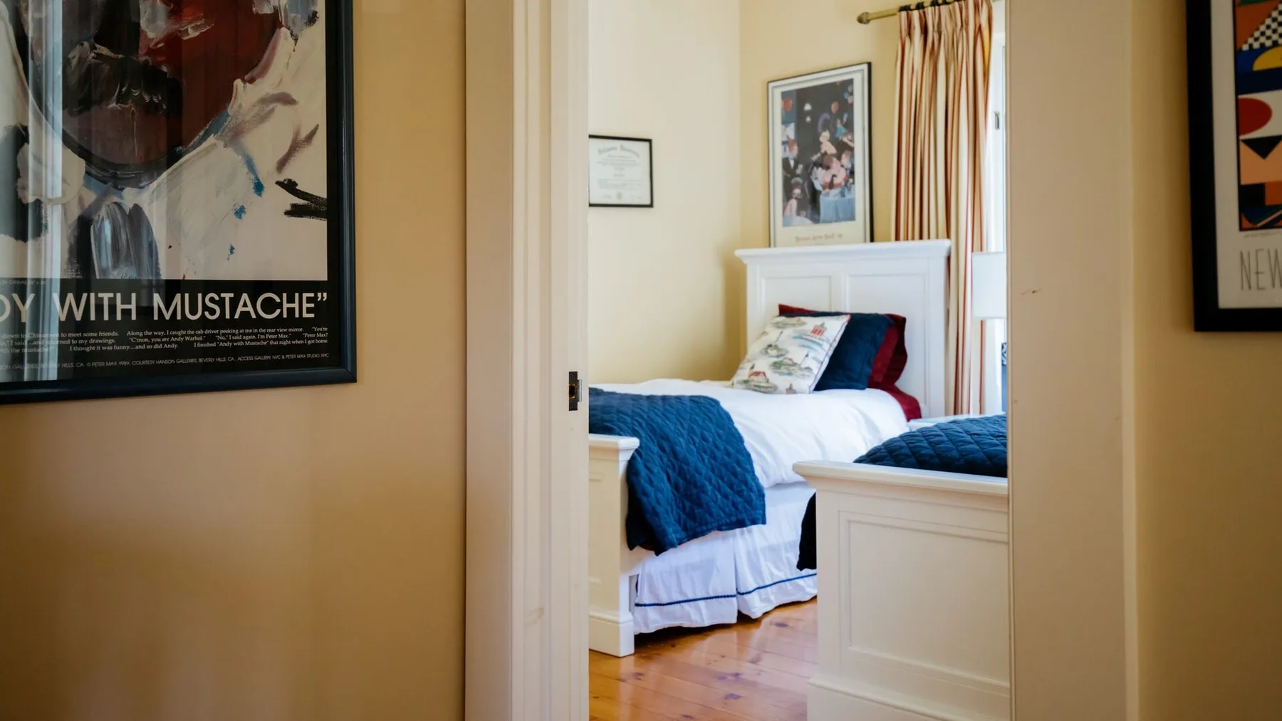 A bedroom with white bedding and blue blankets is visible through the doorway.
