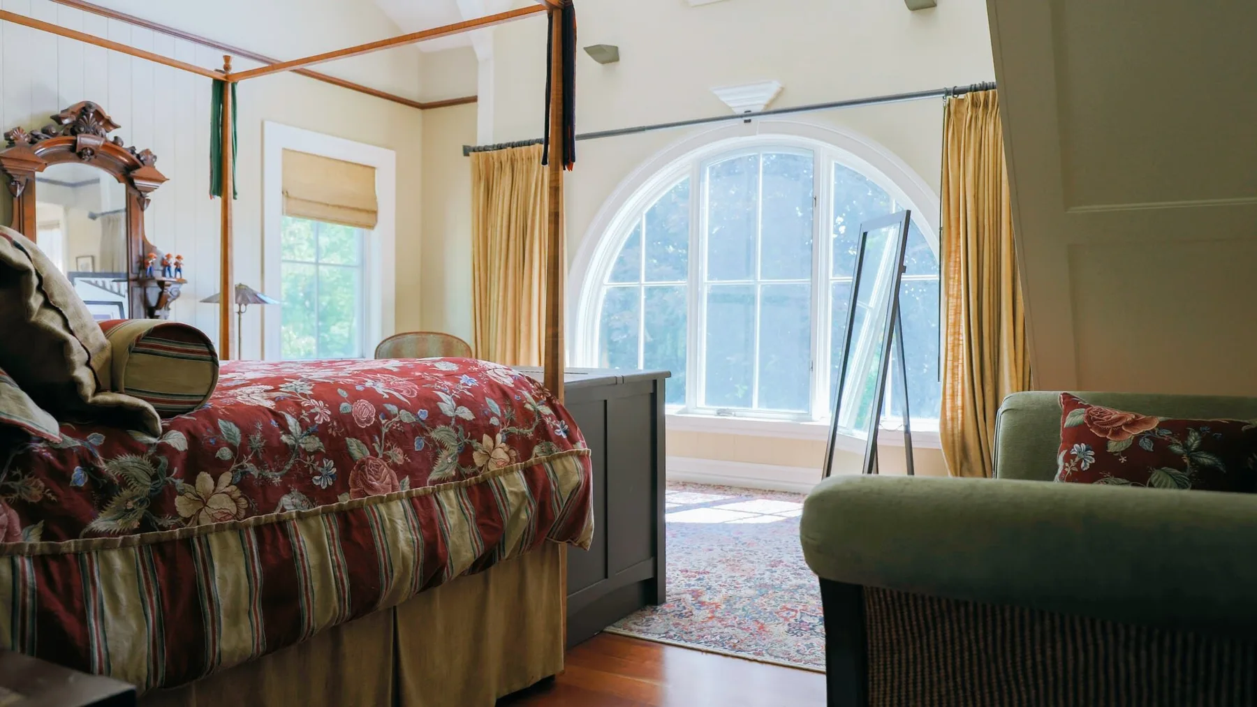 A bedroom with patterned bedding and a large arched window.