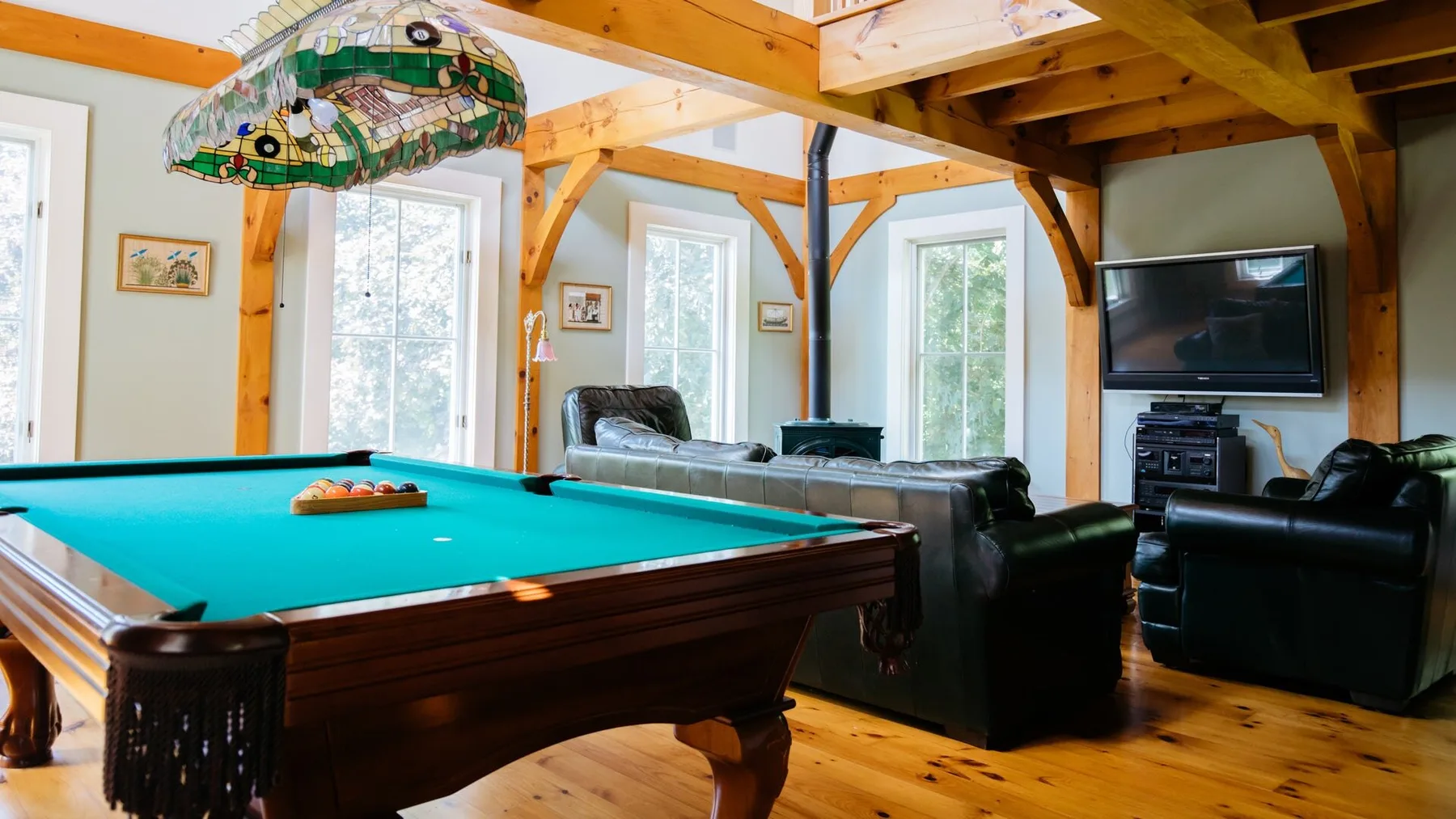 A recreation room with a pool table, seating, and a television.