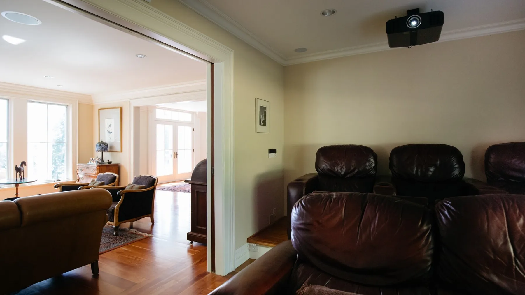 A living room with dark leather seating and a wall-mounted projector.