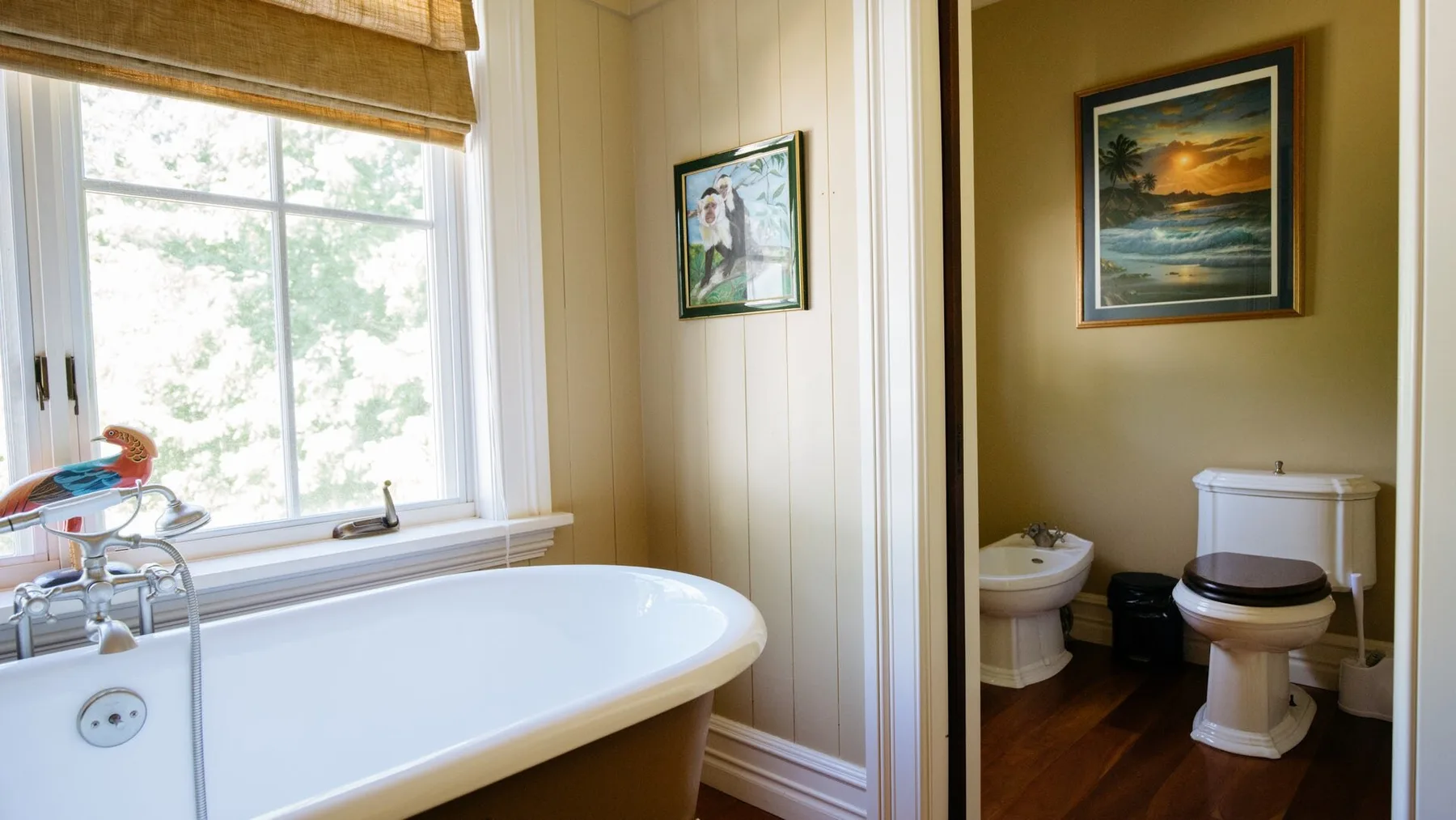 A bathroom with a bathtub beside a window and a toilet in a separate alcove.
