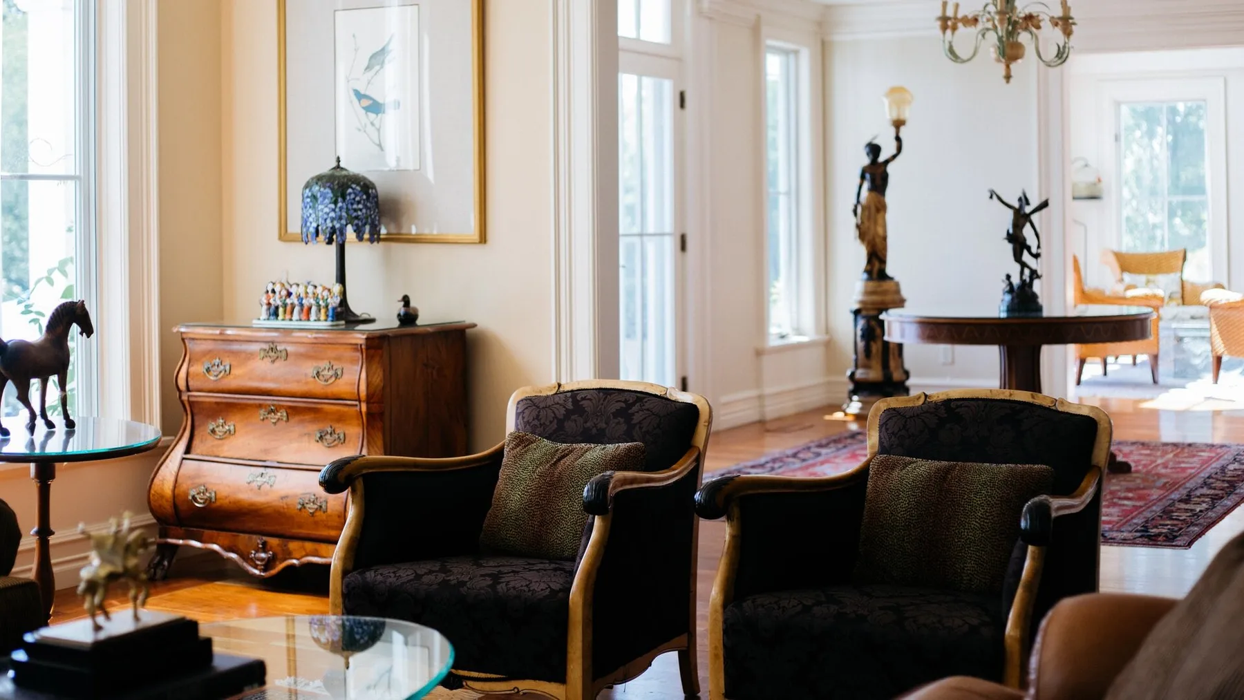 A bright living room with upholstered seating, a wooden chest, and a piano.