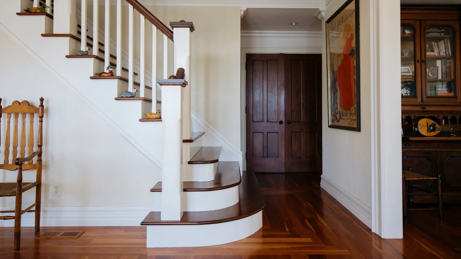 An interior hallway features a curved staircase and a dark wooden door.