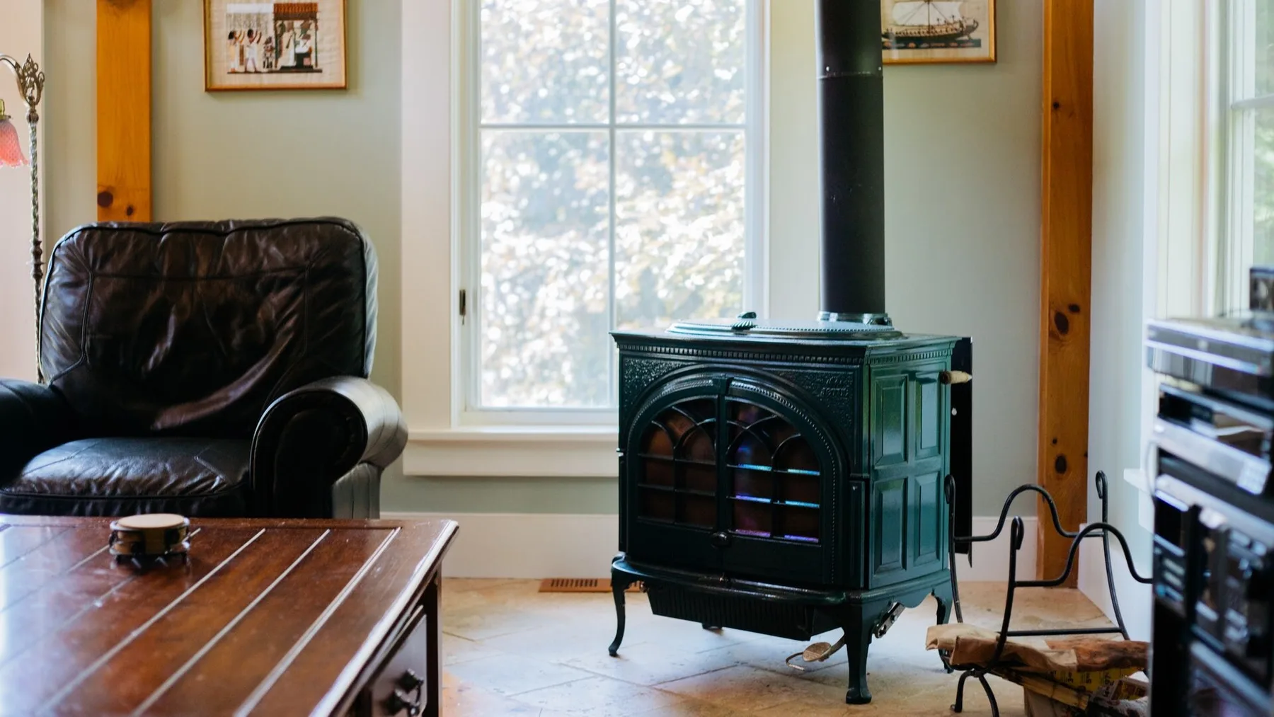 A living room with a dark stove beside a window and leather seating.