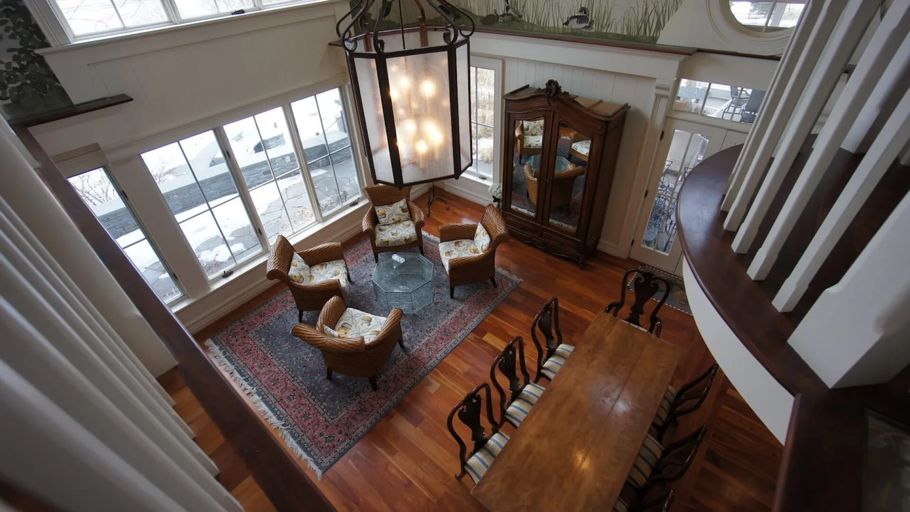 A bright living and dining area with large windows and a wooden dining table.