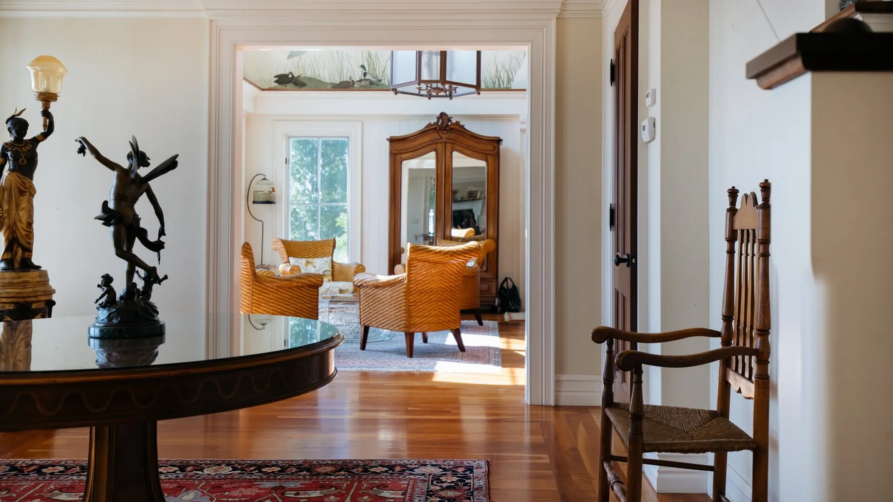 A bright sitting room with wicker seating, a wooden cabinet, and hardwood flooring.