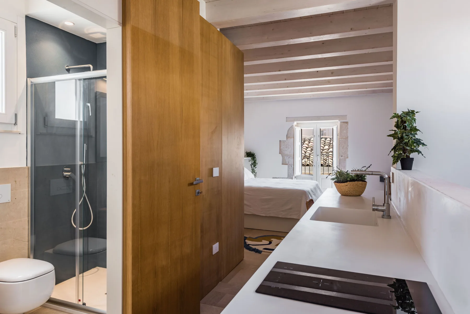 A bedroom with an adjoining shower area and a long white countertop.