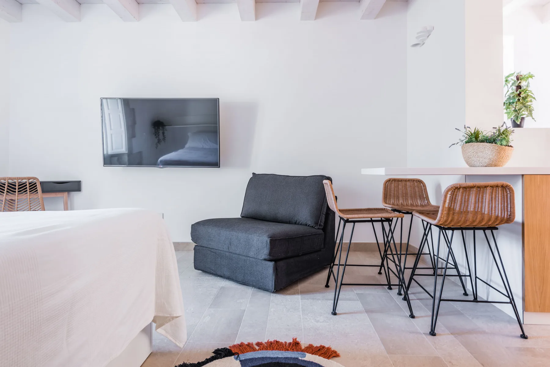 A bright living area with a dark armchair beside a kitchen counter and stools.