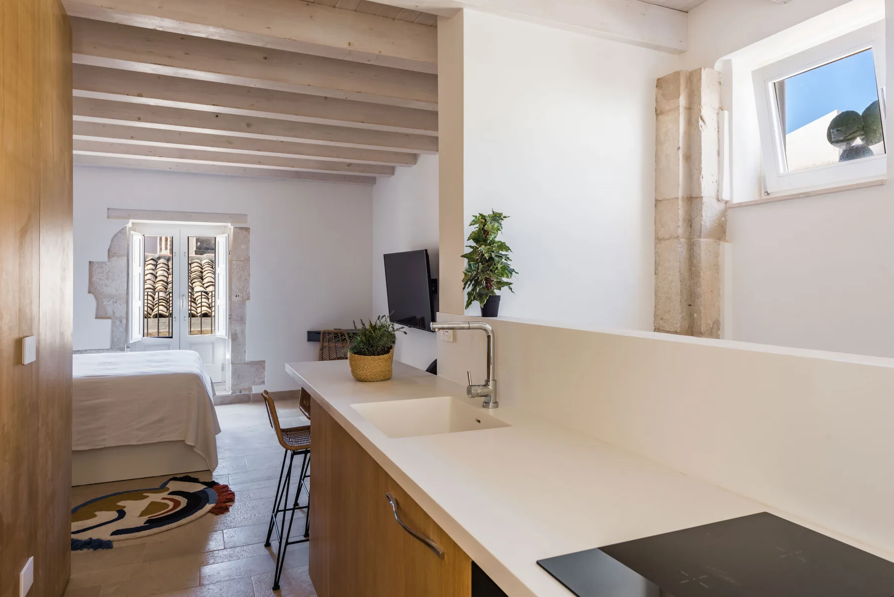An open-plan bedroom and kitchenette with a bed, counter, and dining seating.