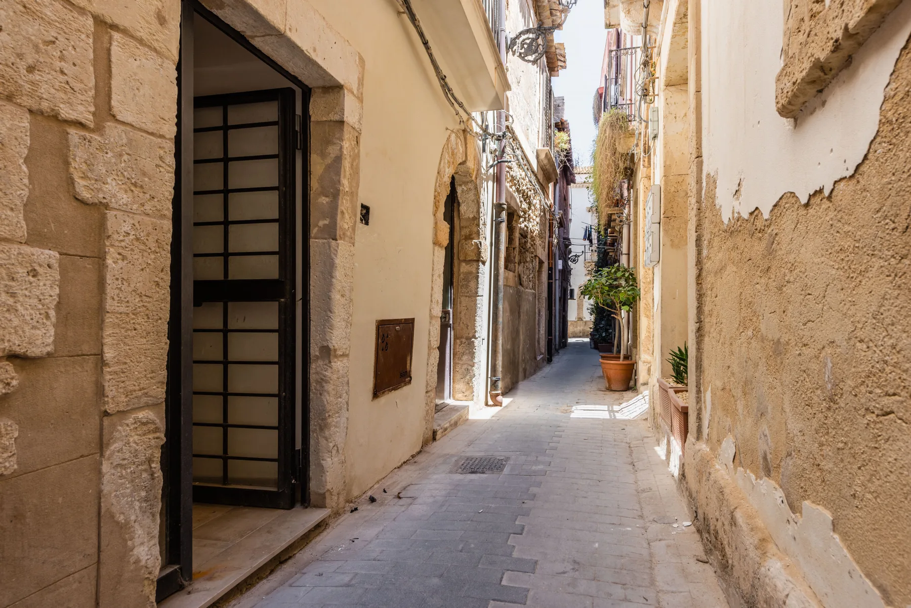 A narrow paved alley runs between old stone and plaster buildings.