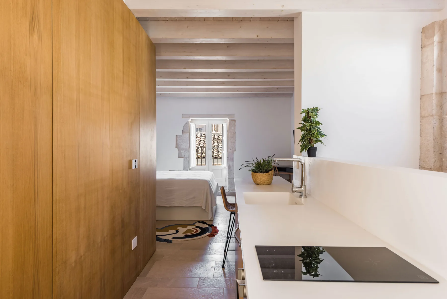 A bright bedroom with a bed beside a long white counter.