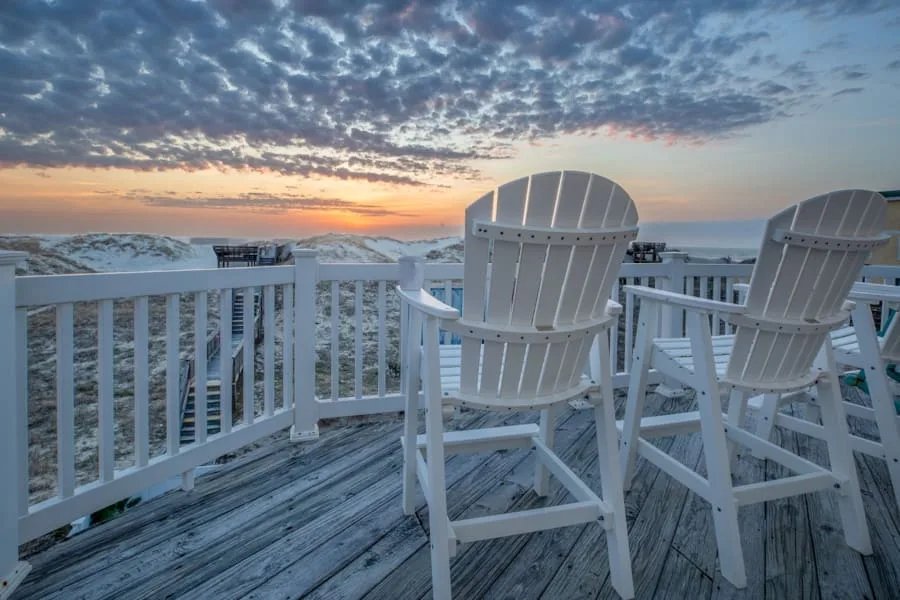 Una terraza junto al mar con asientos blancos da al agua al atardecer.