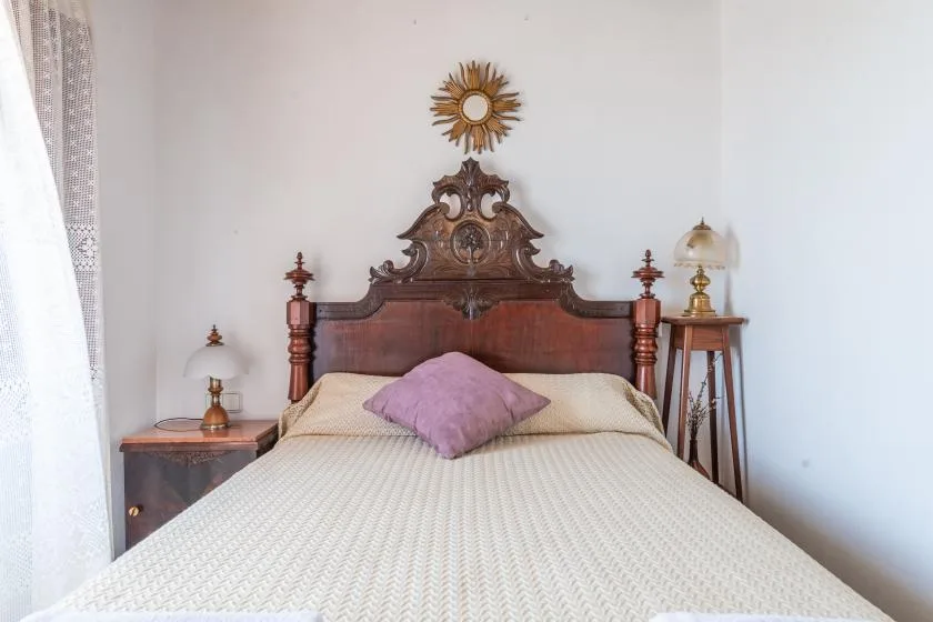 A bedroom with a neatly made bed and an ornate wooden headboard.