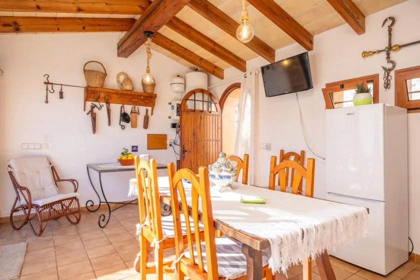 A dining area with a long table and wooden seating beneath exposed ceiling beams.