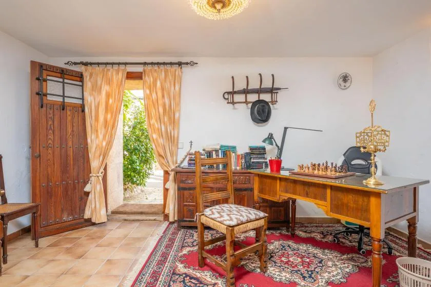 A study with a wooden desk and chair beside an open doorway.