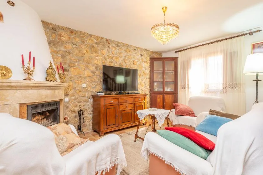 A living room with a stone fireplace, television, and seating around a coffee table.