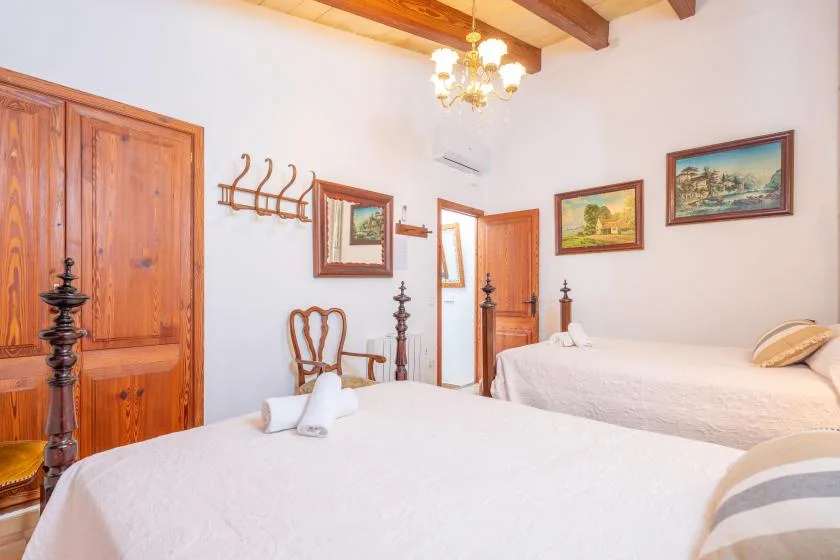 A bedroom with two beds, wooden doors, and framed pictures on the walls.