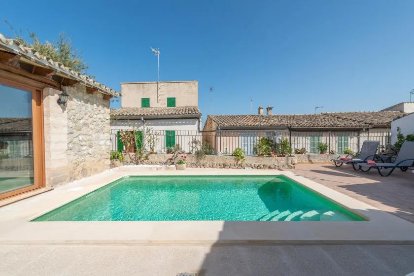 A courtyard pool sits beside a stone building and surrounding patio.