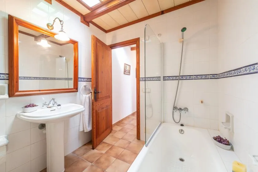 A tiled bathroom with a bathtub, pedestal sink, and wall mirror.