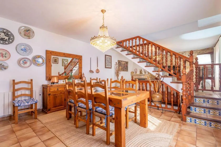 A dining room with a wooden table and chairs beneath a staircase.