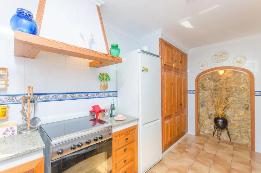 A bright kitchen with a stove, refrigerator, and wooden cabinets.