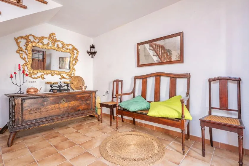 A traditional bedroom with a wooden bed, colorful cushions, and an ornate mirror.