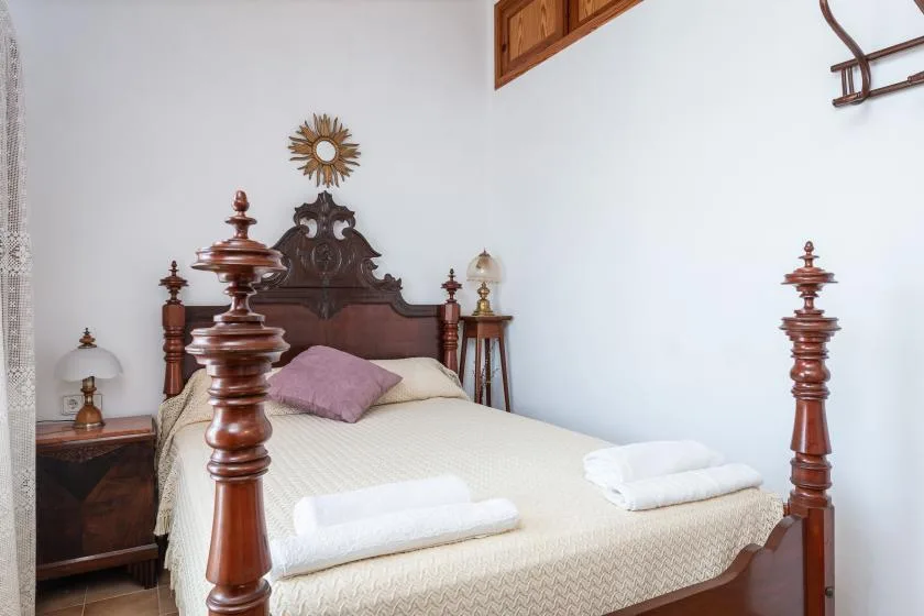 A bedroom with a carved wooden bed and folded white towels.