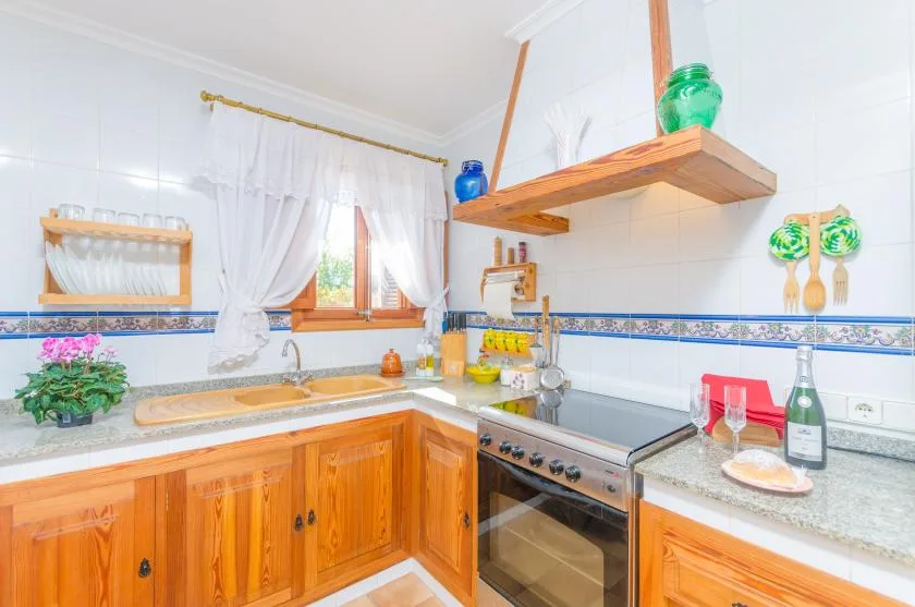 A bright kitchen with wooden cabinets, a stove, and a window above the counter.