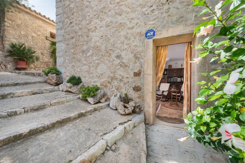 Stone steps lead to an open doorway with a dining area visible inside.
