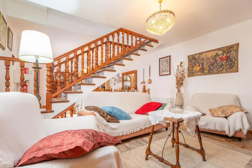 A sitting room with a wooden staircase, upholstered seating, and a small table.