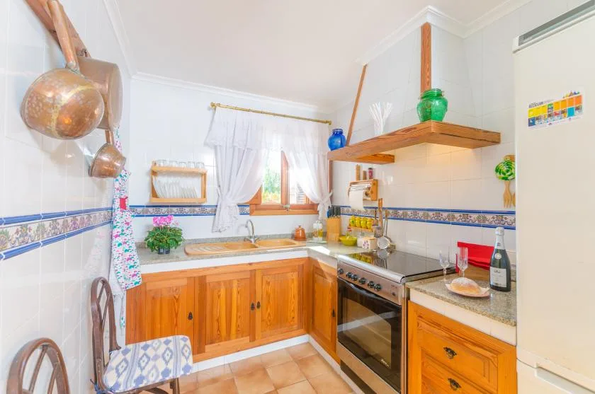 A bright kitchen with wooden cabinets, a window, and a cooking range.