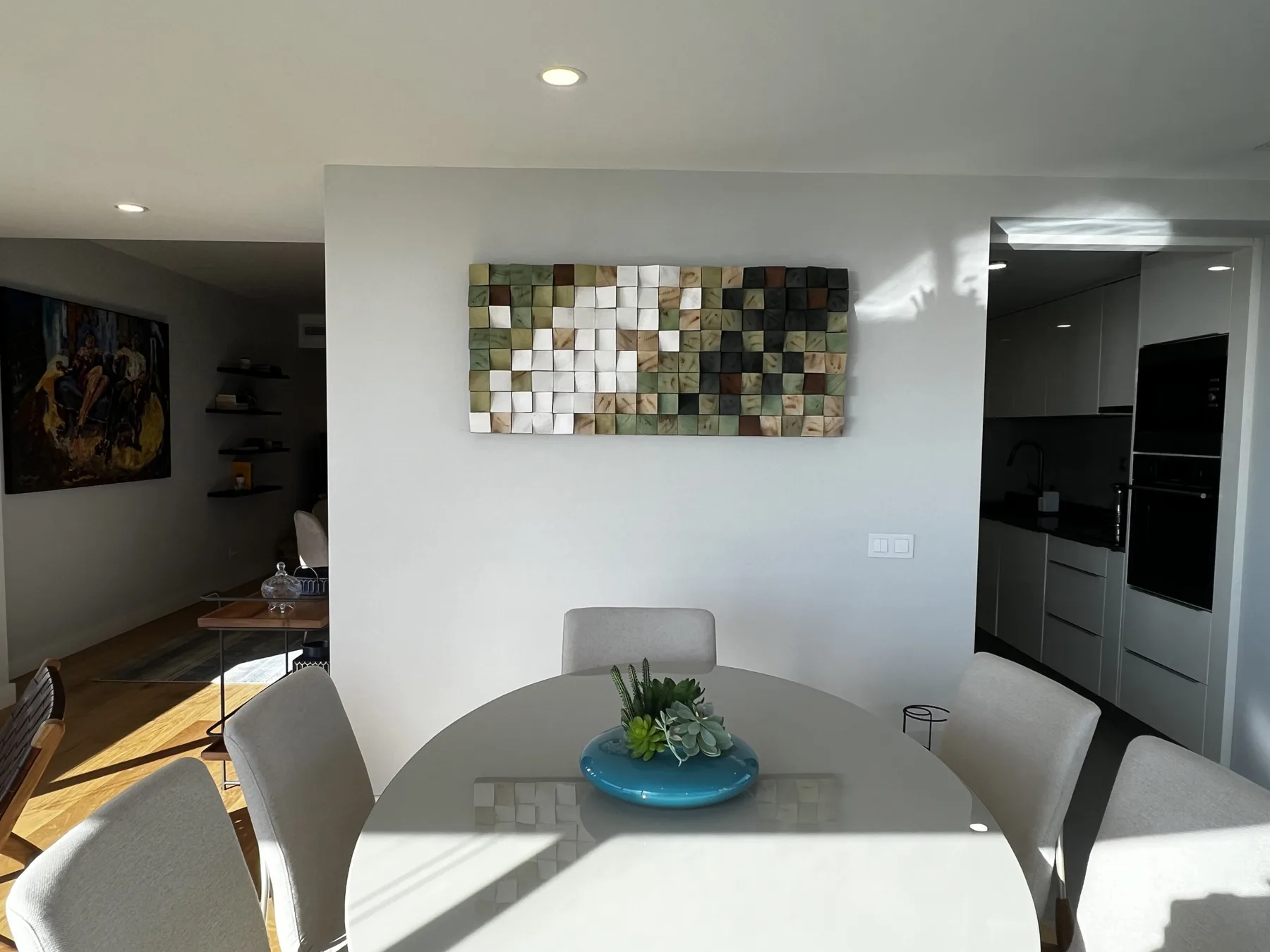 Comedor con mesa, sillas y una obra de arte abstracta en la pared.