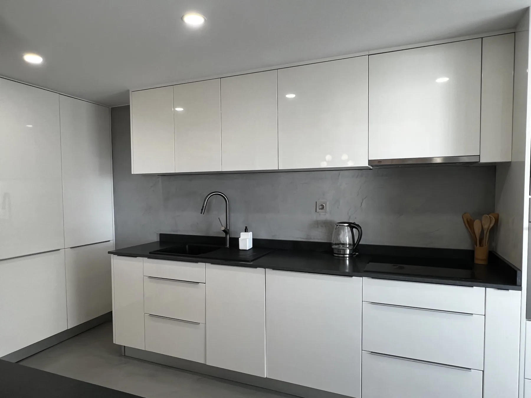 A modern kitchen with white cabinets and dark countertops.