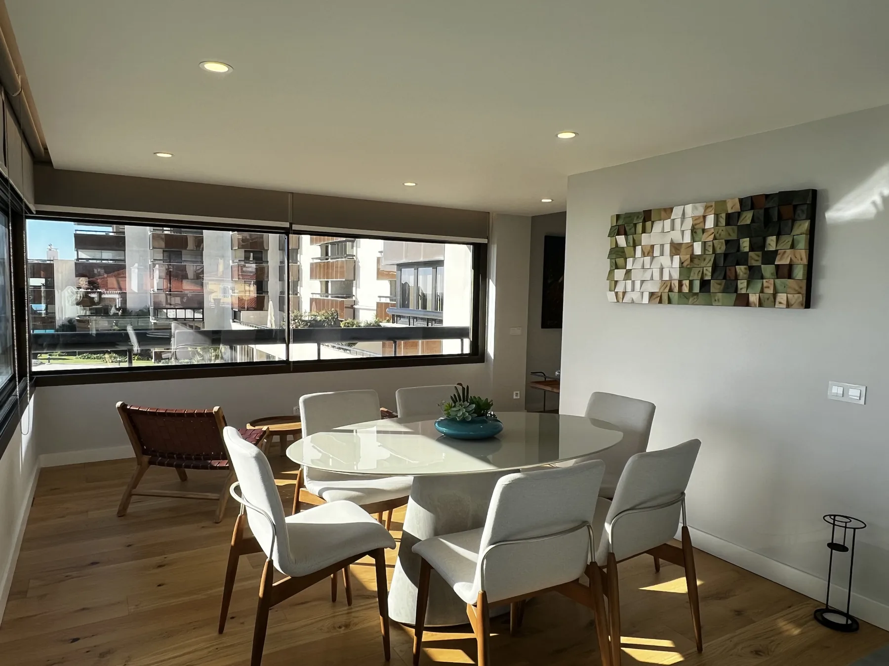 A dining area with a table and chairs sits beside large windows.