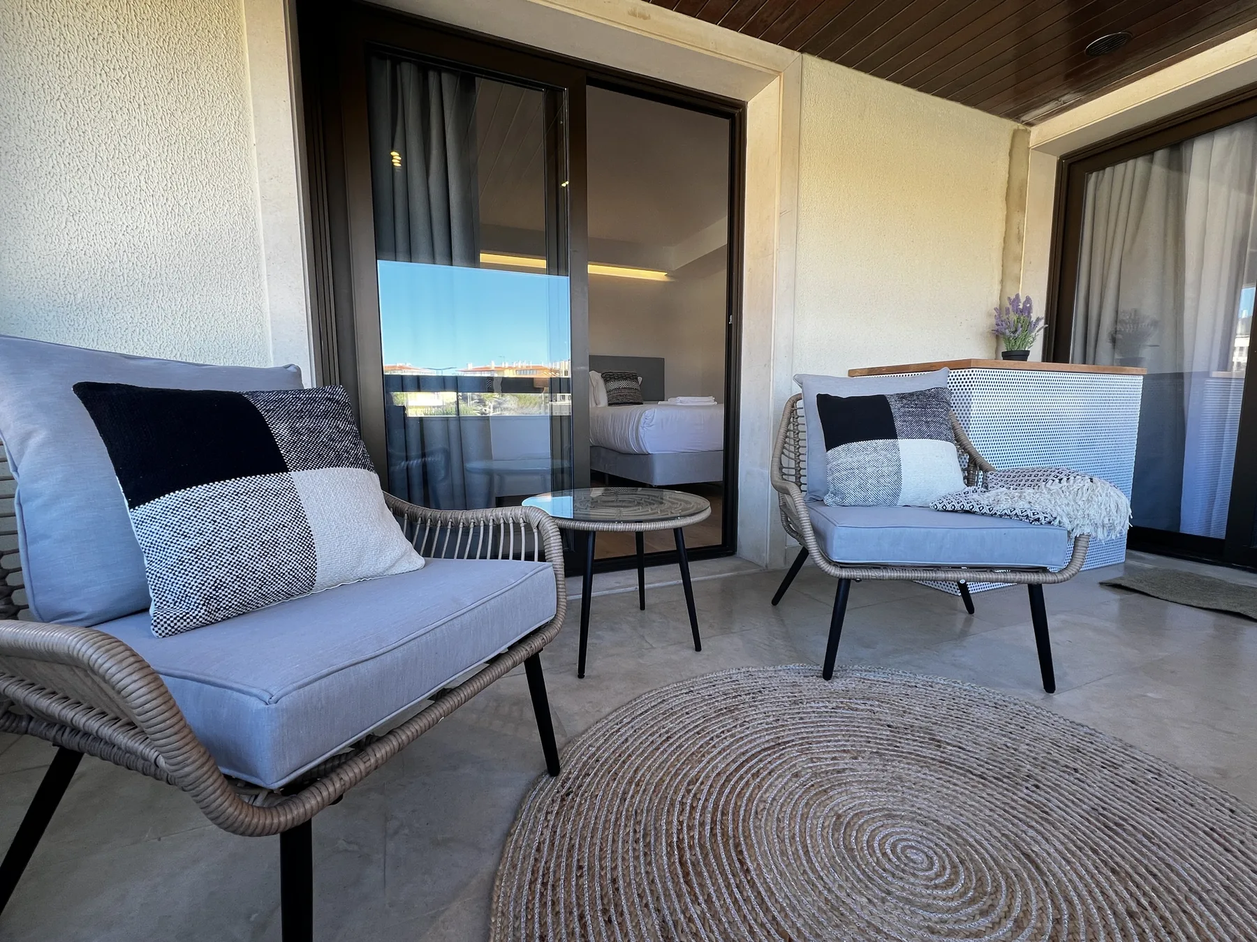 A furnished balcony seating area with a small table and sliding glass doors.