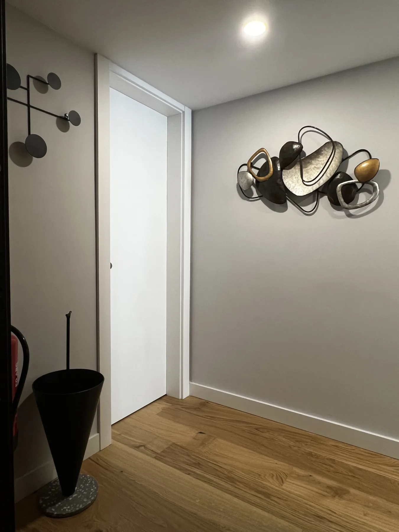 A hallway with wood flooring and abstract wall decorations.