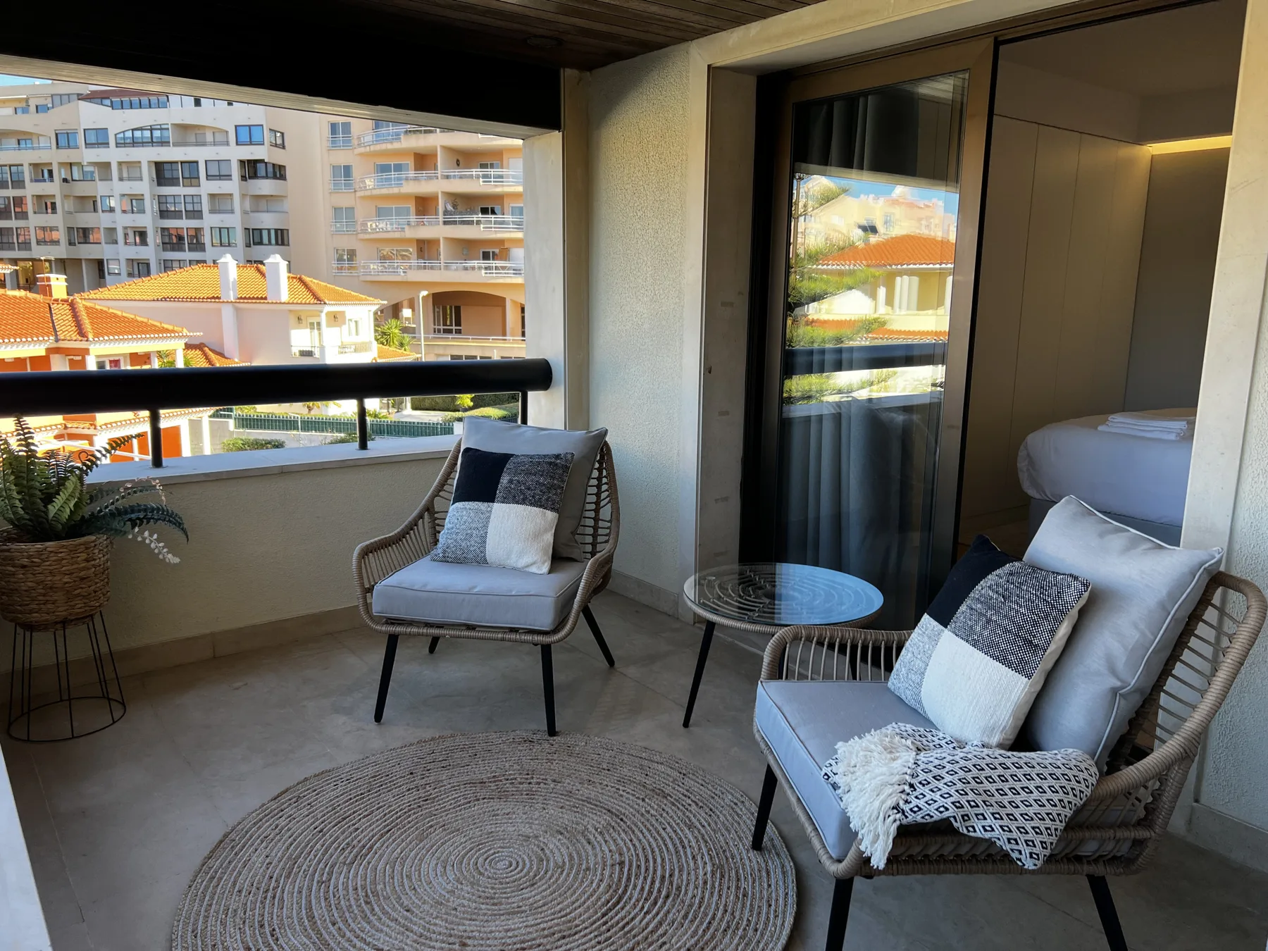 A furnished balcony seating area overlooks nearby buildings and terracotta rooftops.