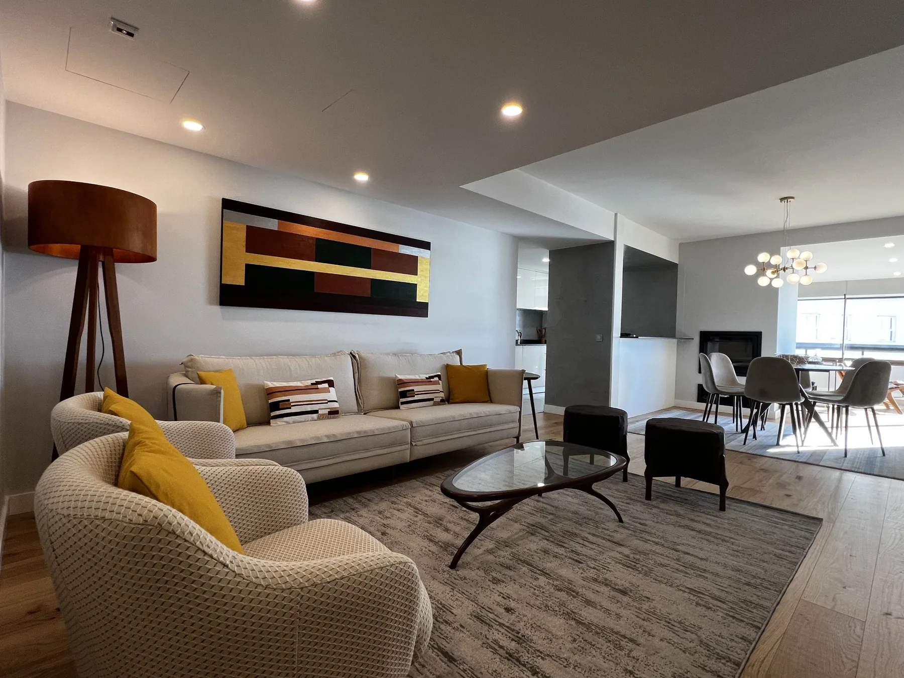 A modern living room with seating, a coffee table, and a dining area.