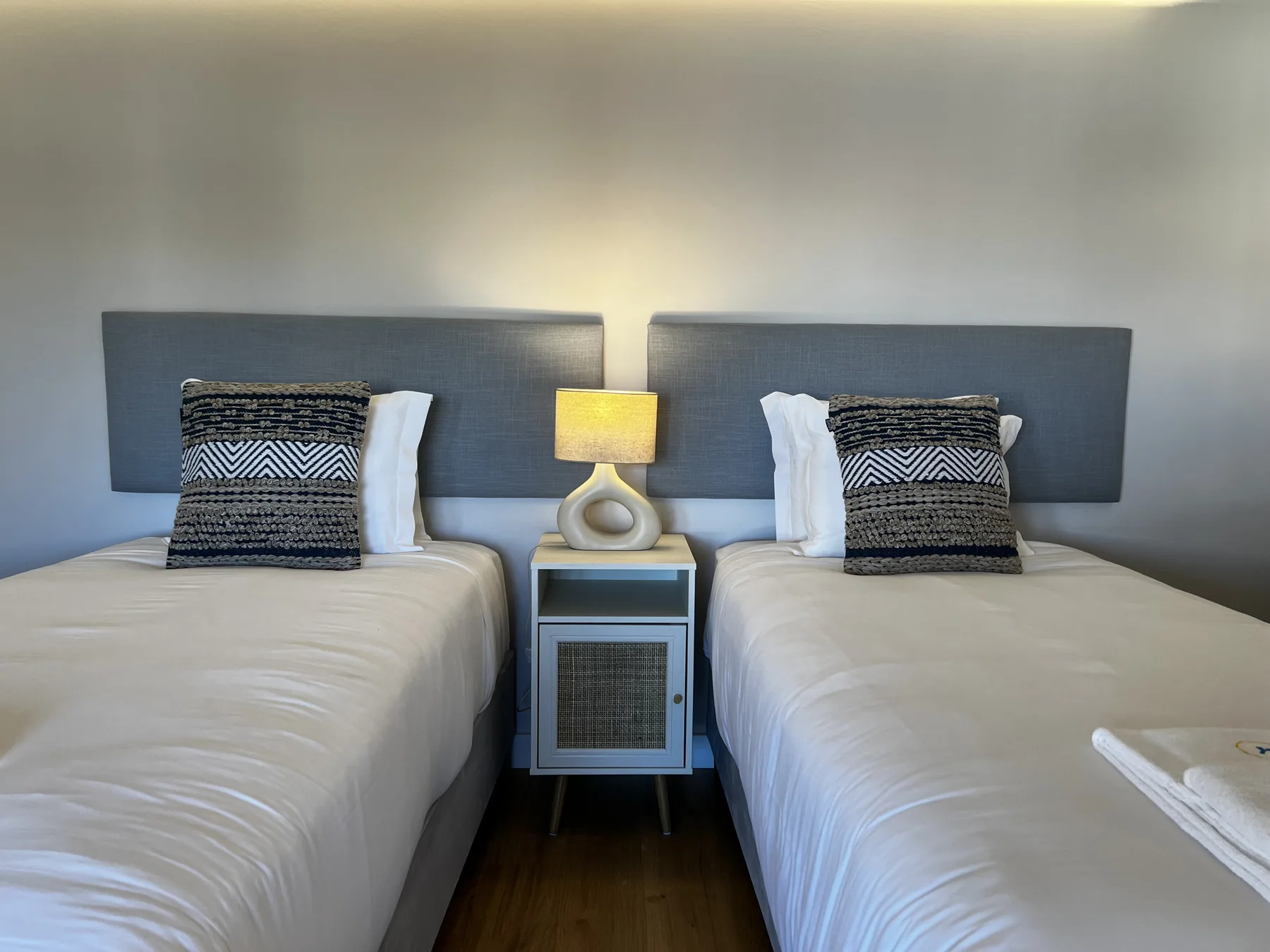 A bedroom with two beds and a small bedside table between them.