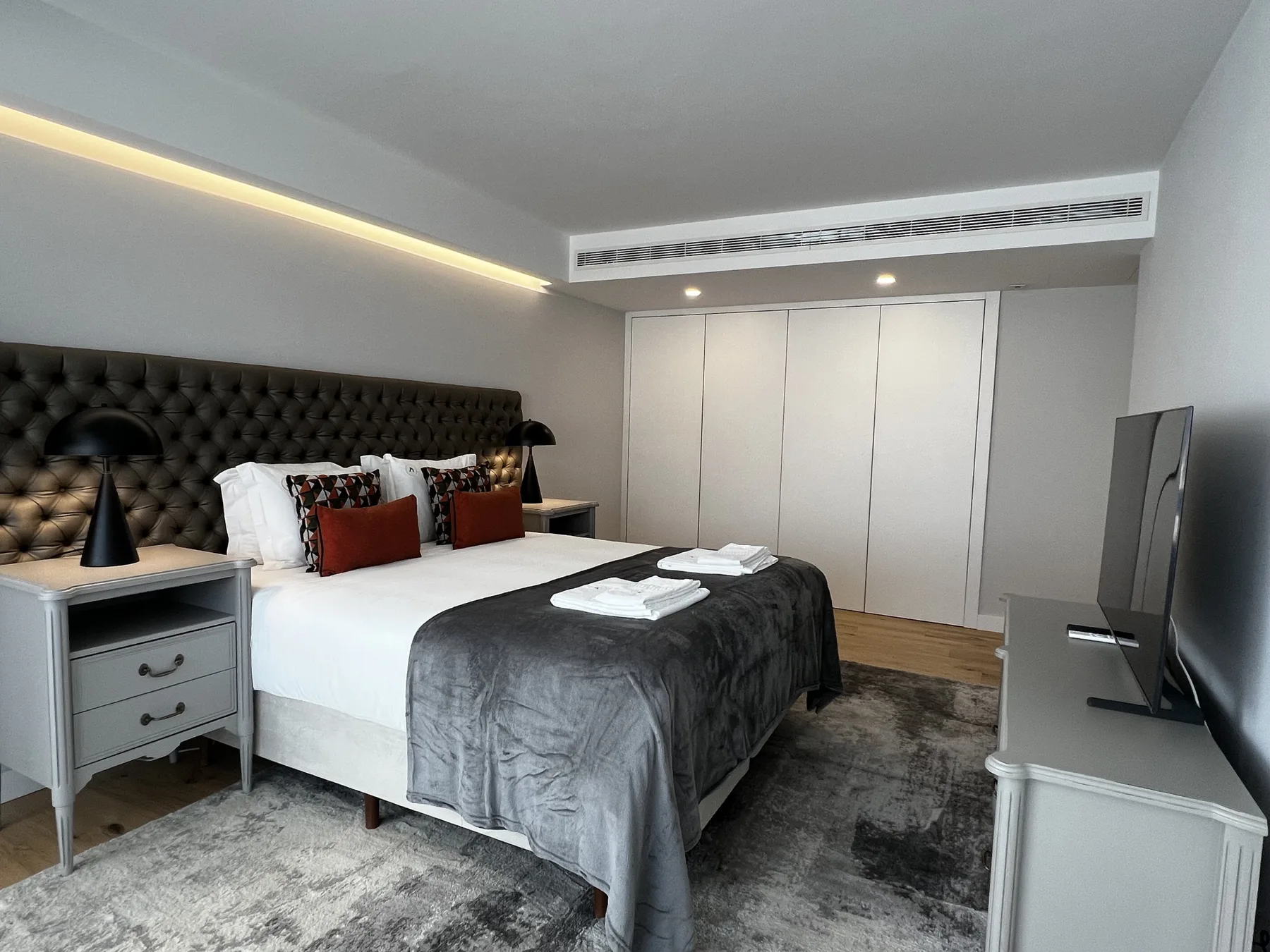 A bedroom with a bed, bedside tables, and a television.